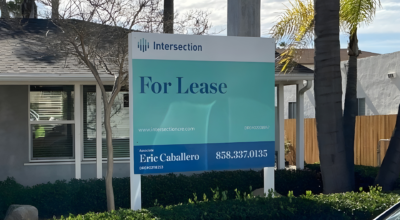 Commercial building with a “For Lease” real estate sign by Intersection displaying agent Eric Caballero and phone number in front of landscaped property.