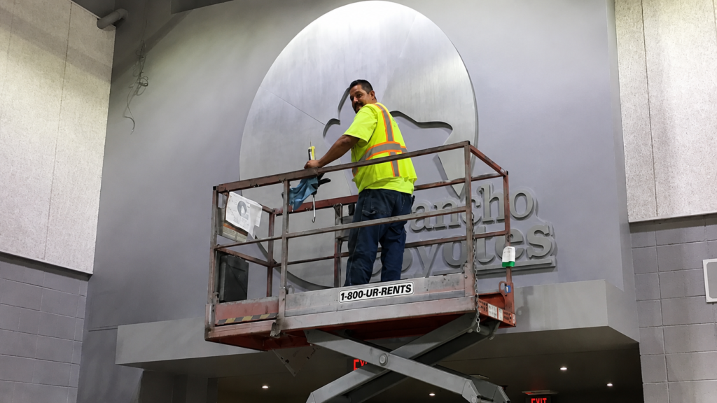 rofessional sign installer using a scissor lift during a commercial sign installation project in San Diego.