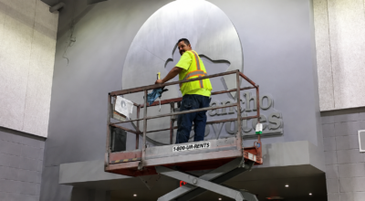 rofessional sign installer using a scissor lift during a commercial sign installation project in San Diego.