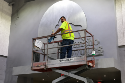 rofessional sign installer using a scissor lift during a commercial sign installation project in San Diego.